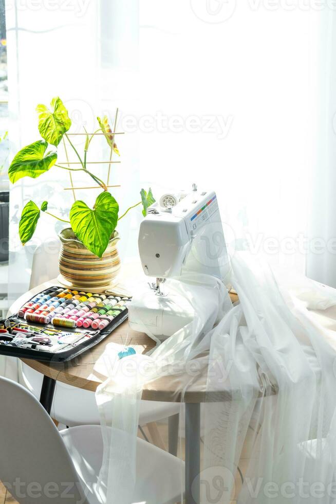de coser diseño con multicolor carretes de hilo de cerca, agujas, eléctrico de coser máquina. relleno el hilo dentro el de coser aguja, ajustando el tensión. pasatiempo, hogar negocio foto