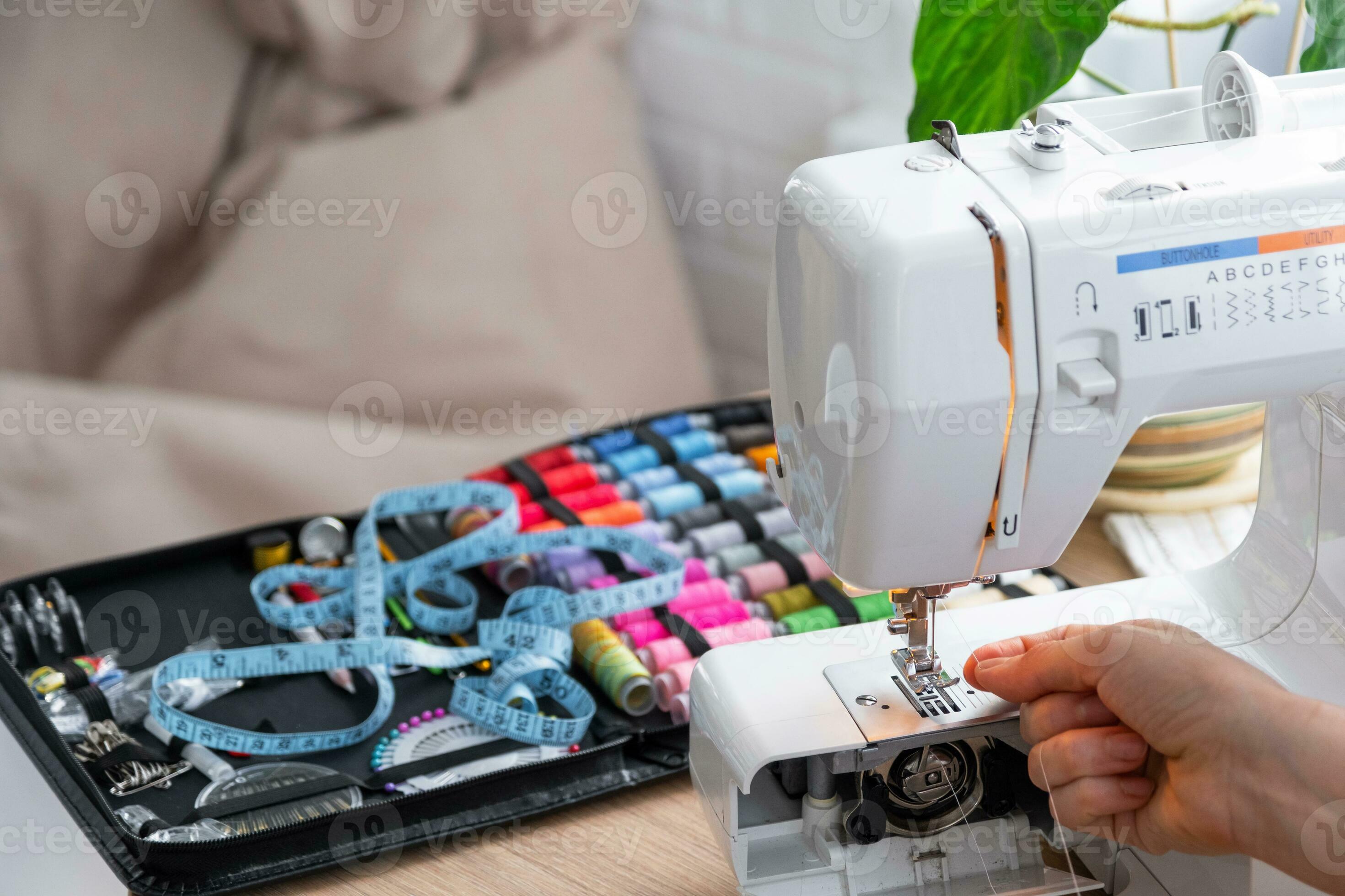 Woman hand close up sews tulle on electric sewing machine. Filling the thread into the sewing