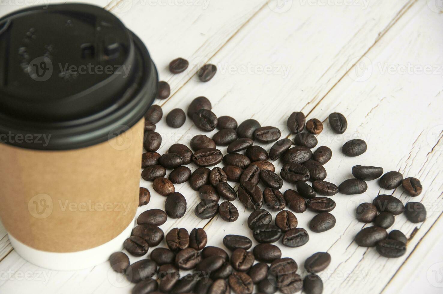 Takeaway coffee cup surrounded with coffee beans with customizable space for text or ideas. Copy space and coffee concept photo