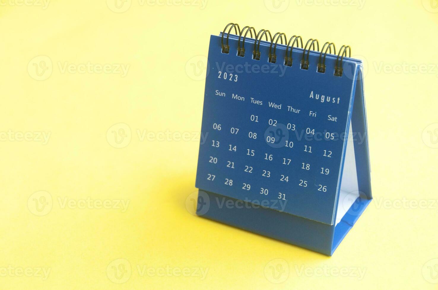 August 2023 blue desk calendar on yellow cover background with customizable space for text. Copy space and calendar concept photo