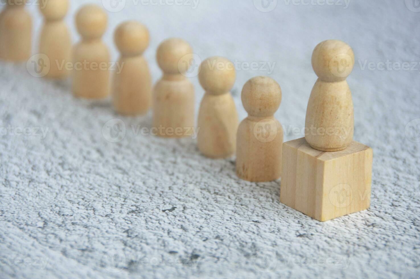 Red wooden figure on top of wooden block representing a leader leading other figure. Leadership concept. photo