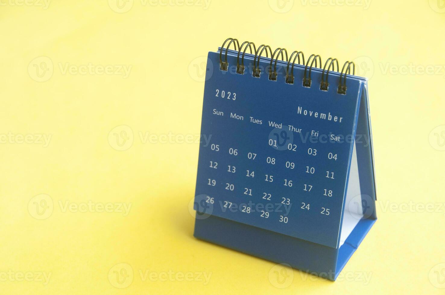 November 2023 blue desk calendar on yellow cover background with customizable space for text. Copy space and calendar concept photo