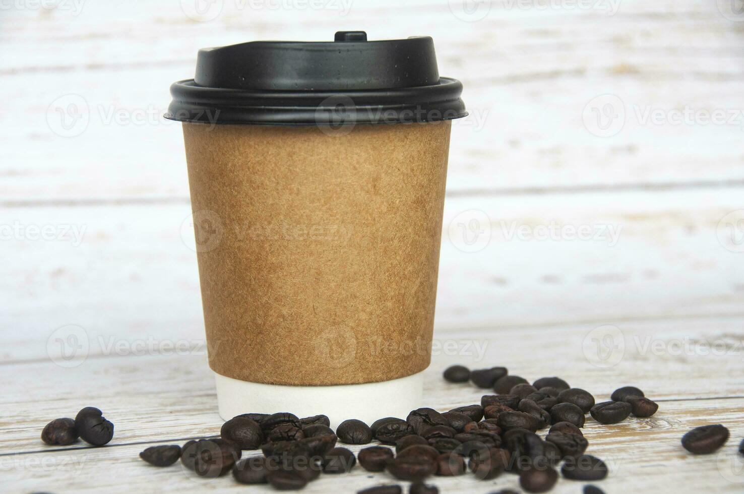 Takeaway coffee cup surrounded with coffee beans with customizable space for text or ideas. Copy space. photo