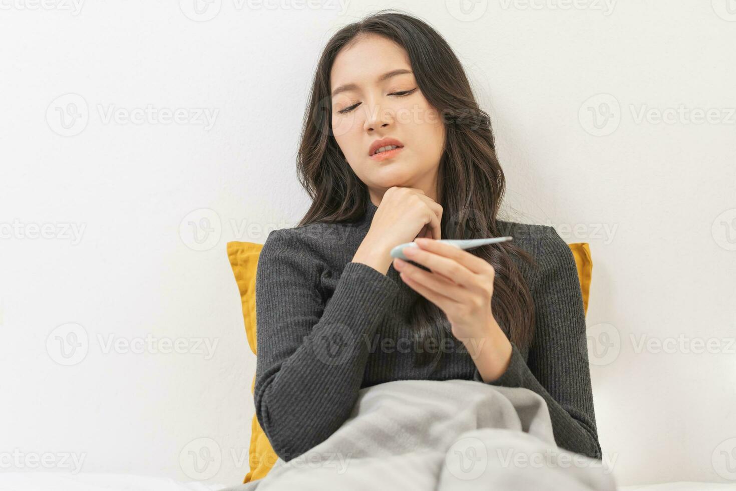 Sick, influenza asian young woman, girl have sore throat, hand using thermometer measure body temperature, check a fever, flu and feeling illness sitting on bed at home. Health care people. photo