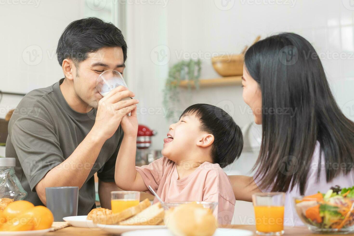 contento refresco familia desayuno en mañana, asiático joven padre padre, madre y pequeño linda chico, niño teniendo comida en cocina comiendo juntos a hogar. alegre, disfrutar Cocinando gente. foto