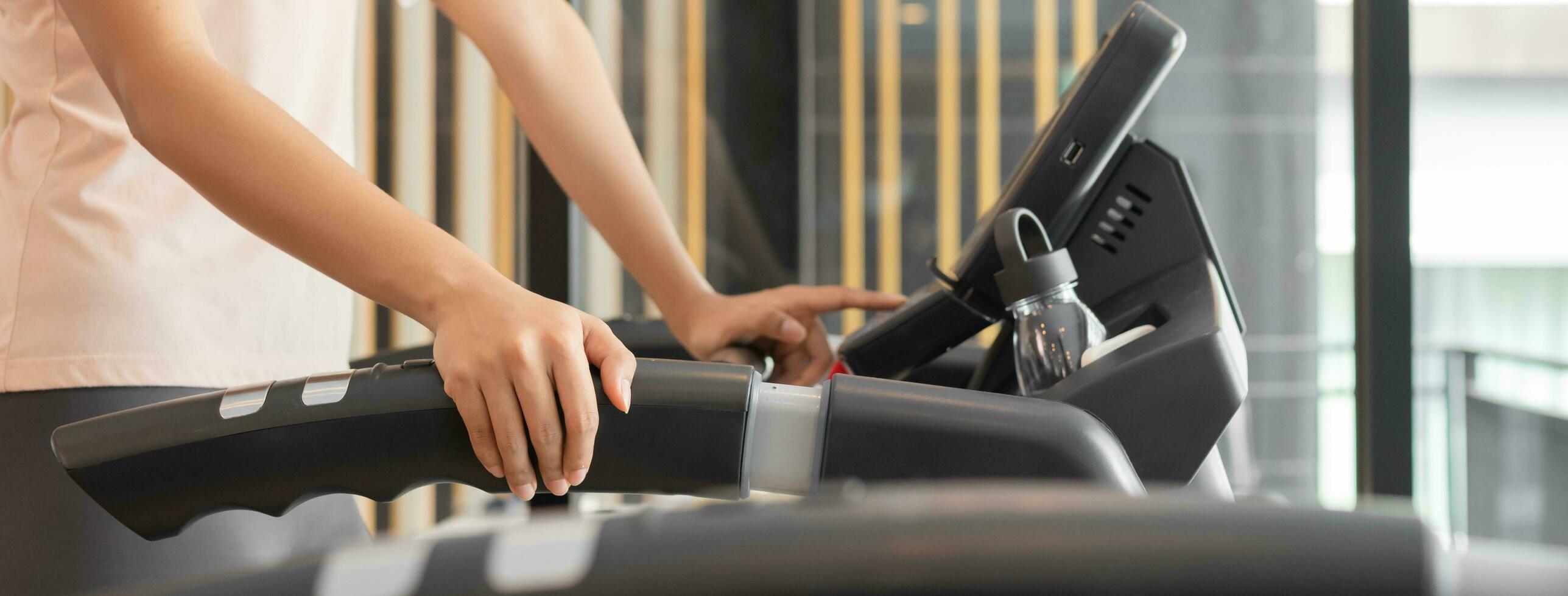 Young woman, girl setting machine ,exercise on elliptical cross trainer in fit sportswear, practice working out training. Sport strong person in gym fitness for healthy lifestyle, recreation concept. photo