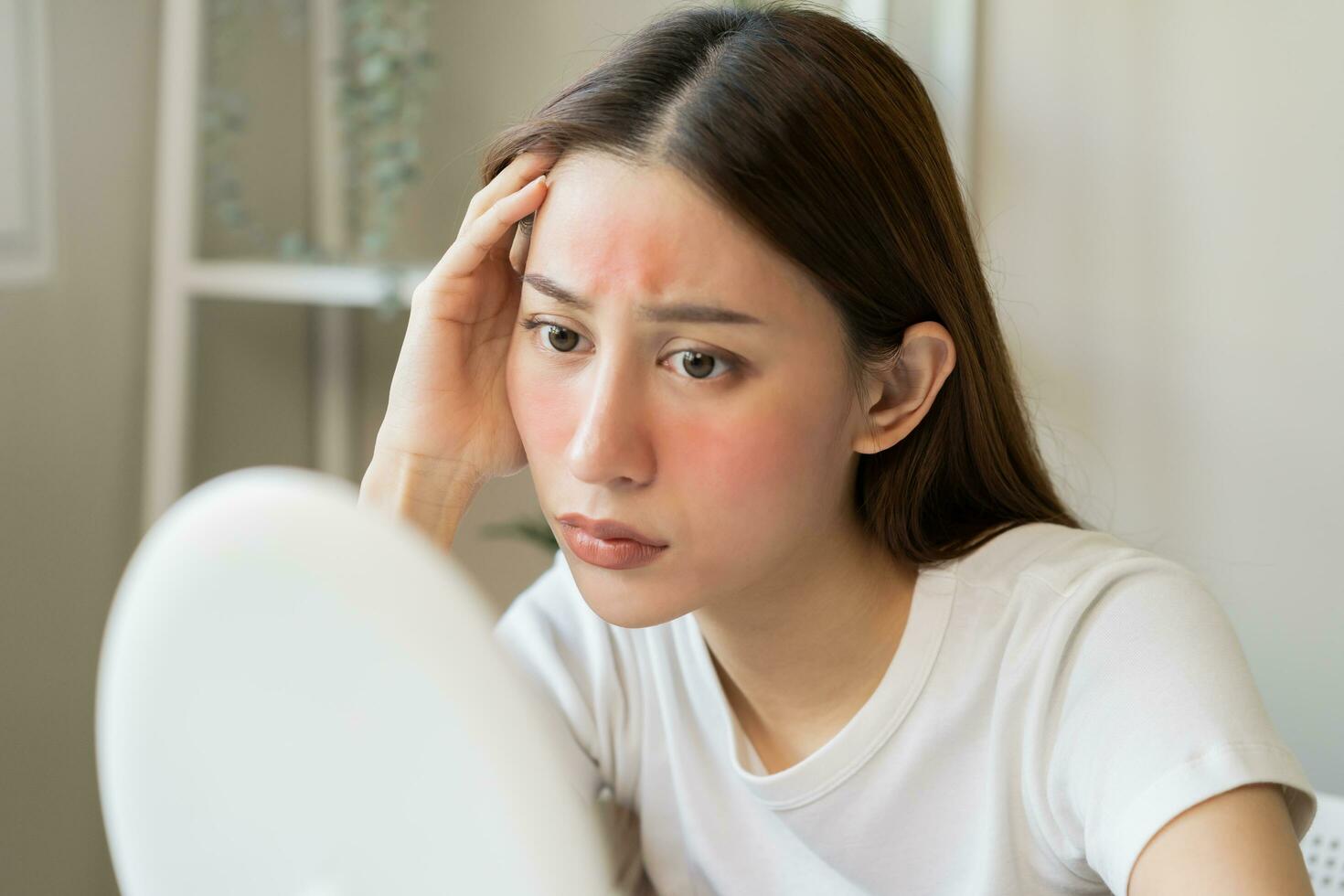 Dermatology, scratch asian young woman looking at mirror, expression worry and itch, itchy allergy or allergic sensitive reaction, red spot or rash on her face. Beauty care from skin problem treatment photo