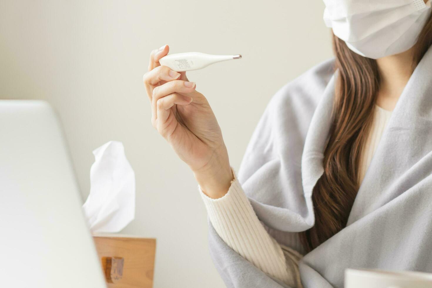 Sick, influenza asian young woman, girl hand use, holding thermometer check measure body temperature, have a fever, flu feel illness sitting work at home, office. Health care, infection of covid-19. photo