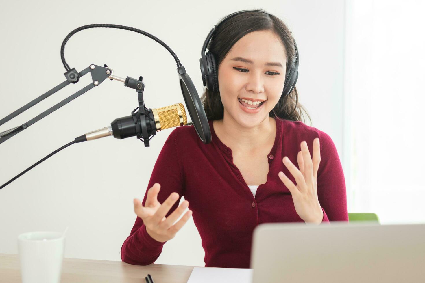 Beautiful asian young woman radio host working in headphones, microphone while talk, conversation and recording podcast, live on social media.Technology of on-air online in broadcasting at studio. photo