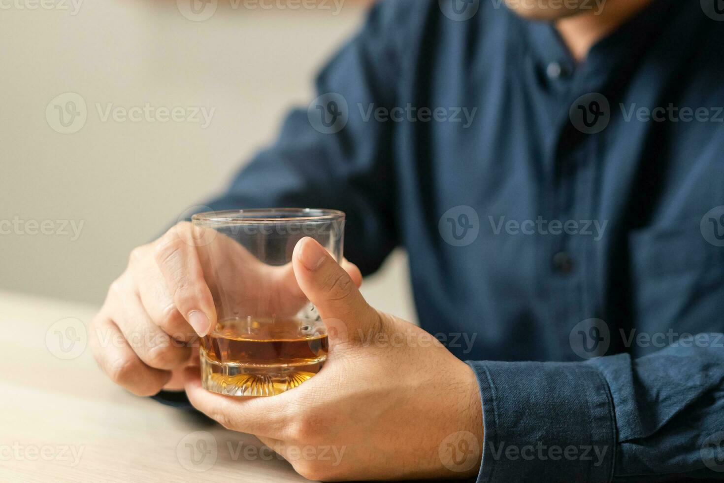 Alcoholism, drunk asian young man, male hand holding a glass of alcohol, whiskey sitting alone, drinking on table at home, at night. Treatment of alcohol addiction, suffer abuse problem alcoholism. photo