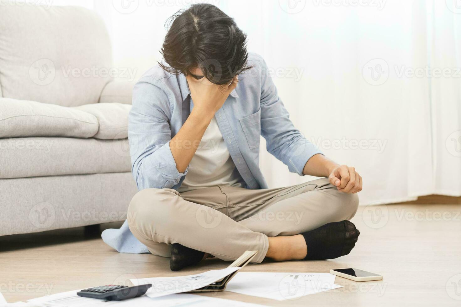 Financial, owe asian man, male sitting on floor home, stressed and confused by calculate expense from invoice or bill, have no money to pay, mortgage or loan. Debt, bankruptcy or bankrupt concept. photo