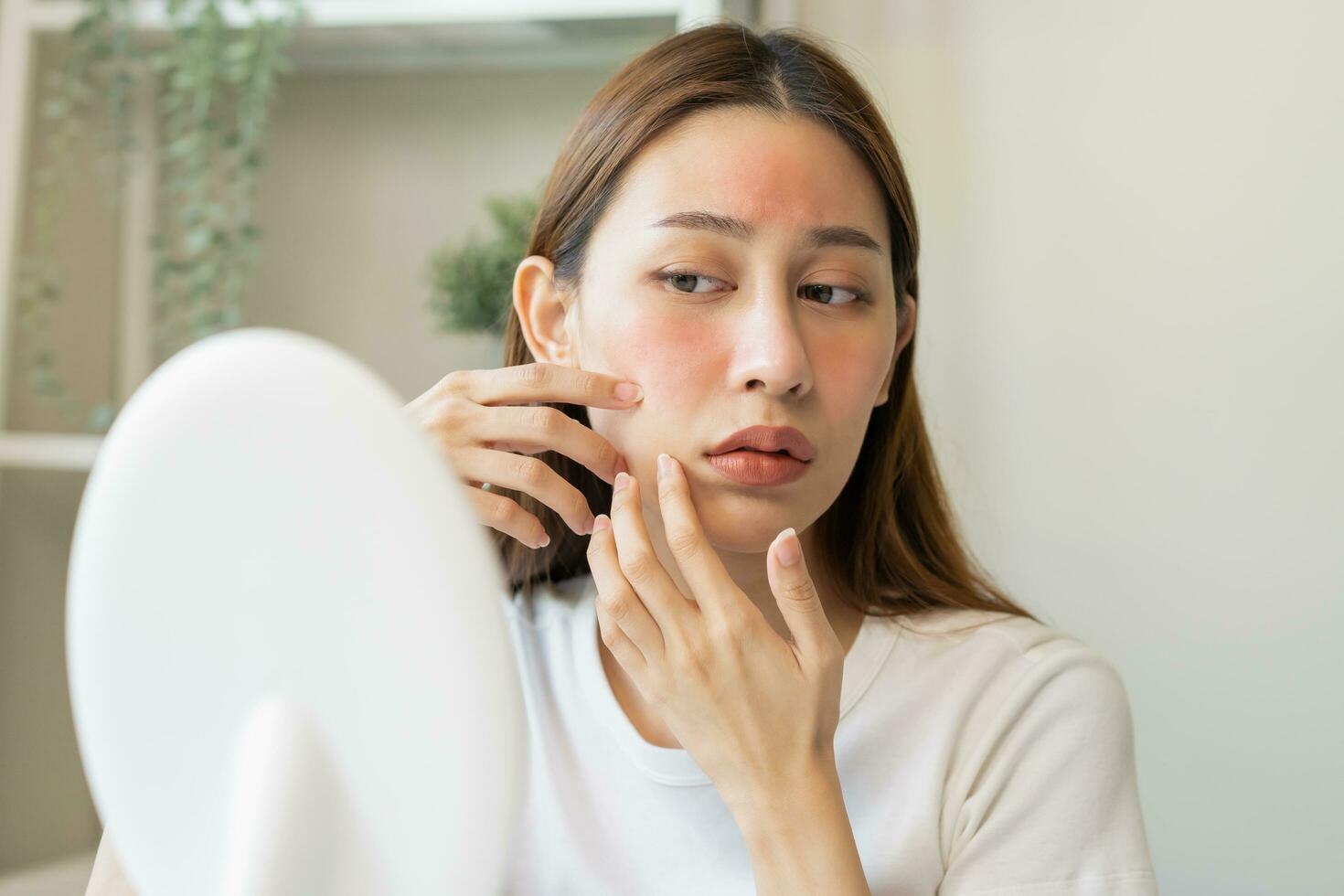 Dermatology, scratch asian young woman looking at mirror, expression worry and itch, itchy allergy or allergic sensitive reaction, red spot or rash on her face. Beauty care from skin problem treatment photo