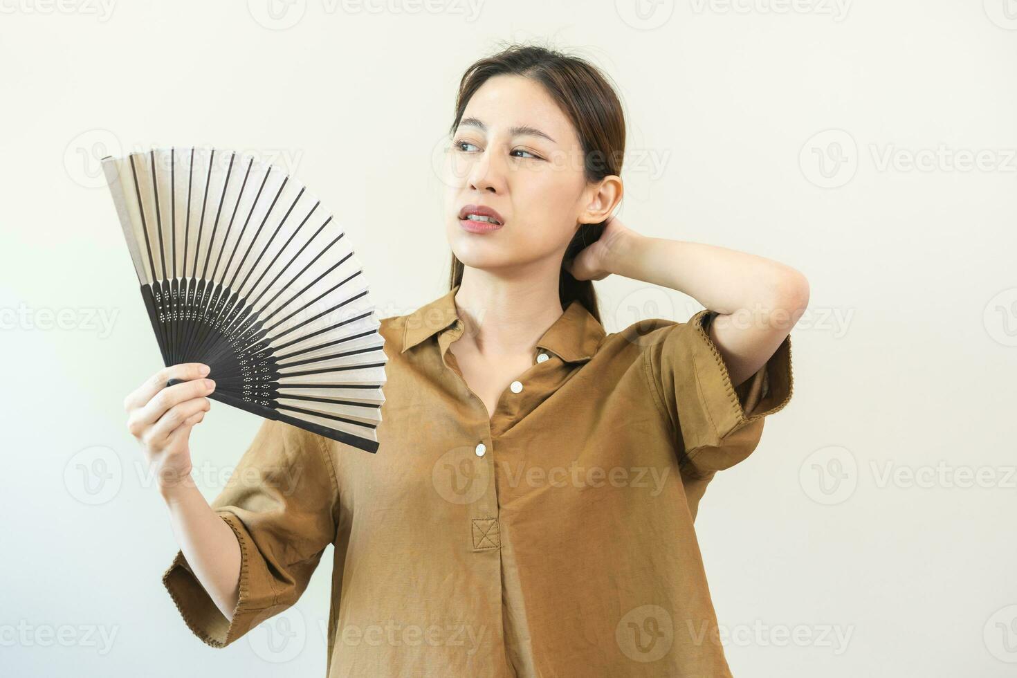 sufrimiento verano calor ataque, caliente clima, cansado asiático joven mujer, niña sudoroso y sediento, refrescante con mano en soplo, ola ventilador a ventilación cuando temperatura alto a hogar, casa en antecedentes foto