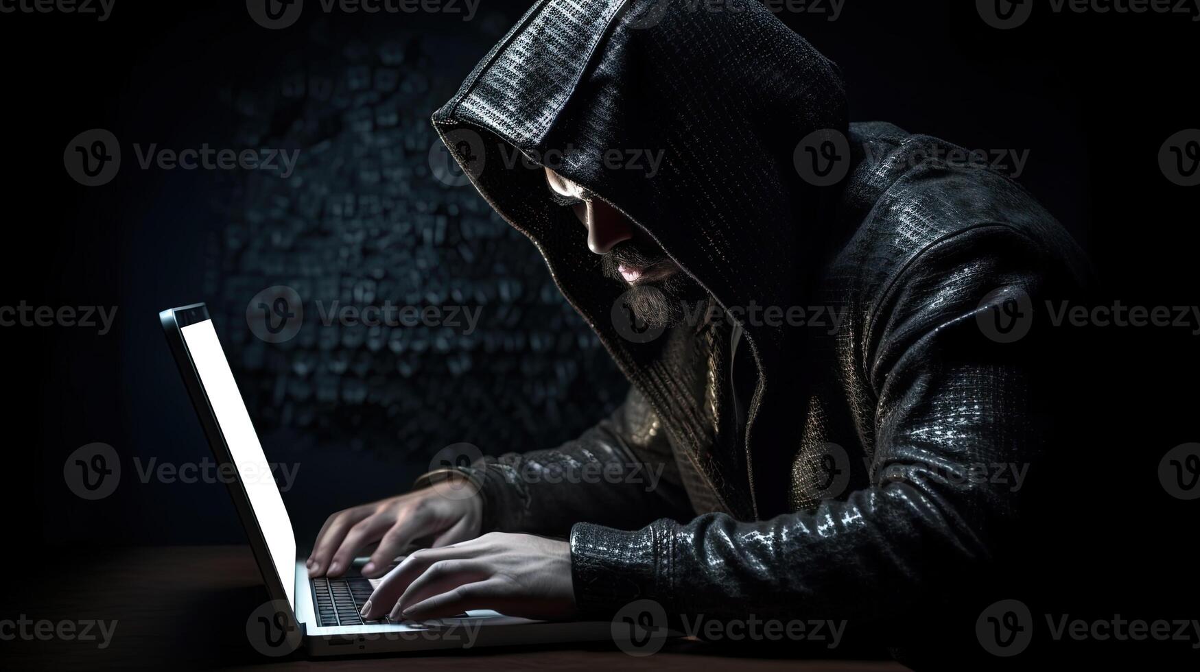 Closeup Portrait of Young Man Wearing Black Hoodie and Using Laptop in Dark Background. Concept of Hacker or Cyber Attack. photo