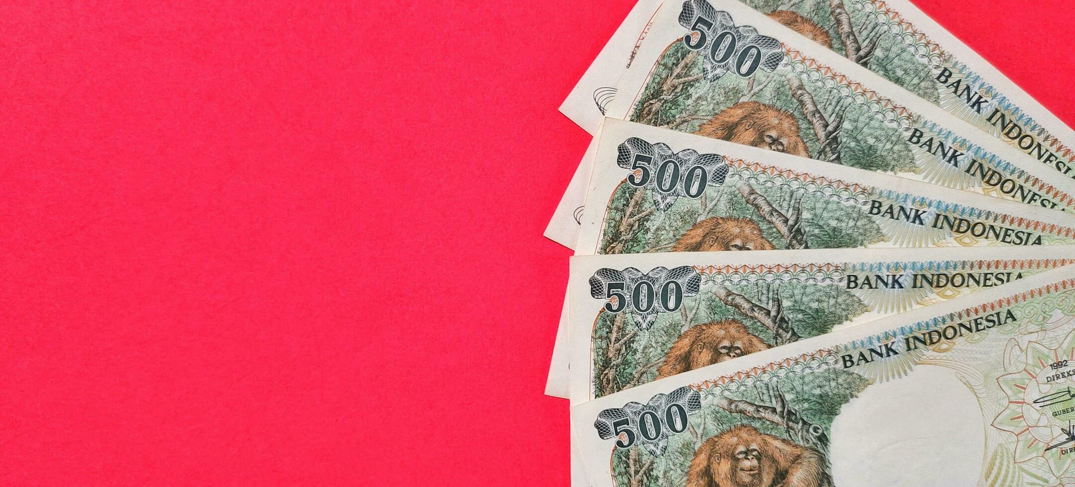 Top view of old Indonesian banknotes Rp.500,00 issued in 1992. Rupiah currency concept isolated on a red background. Selective focus photo
