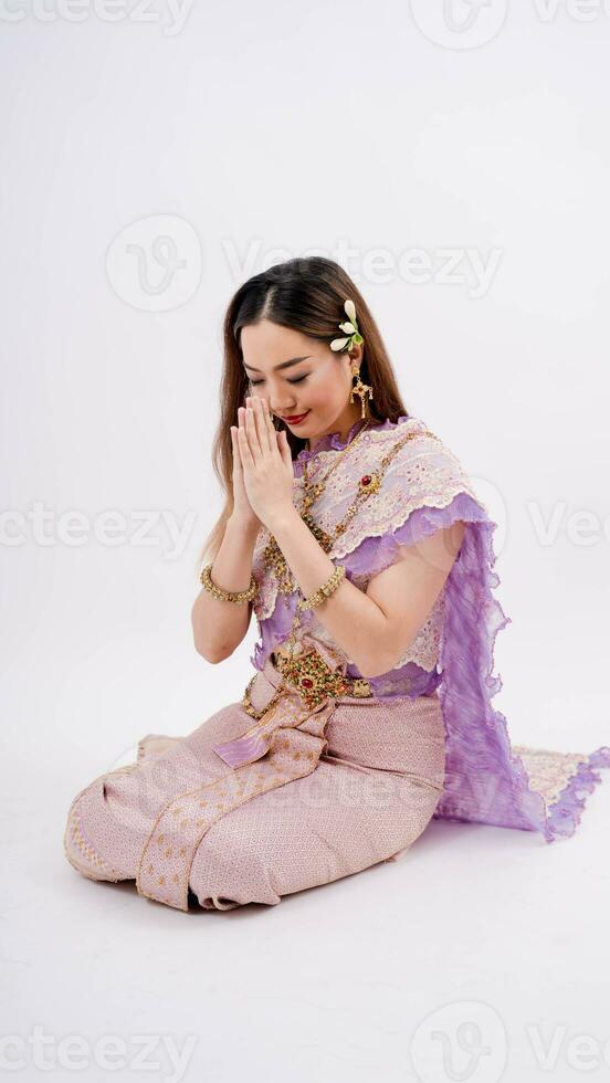 Asian woman wearing typical, traditional Thai dress with identity Thai culture posing to pay respect with smiling, isolated on white background photo