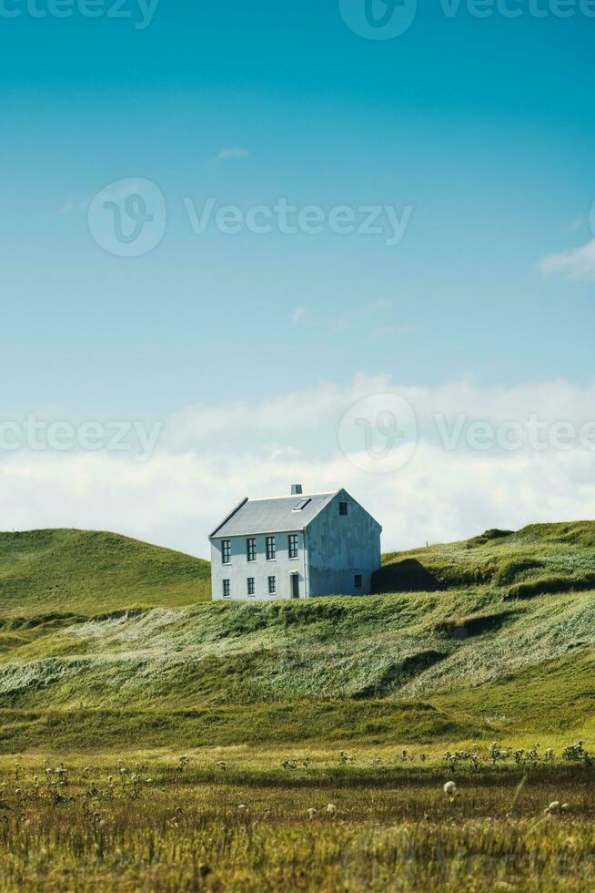 Nordic house on hill among the farmland in countryside on bright day at Iceland photo