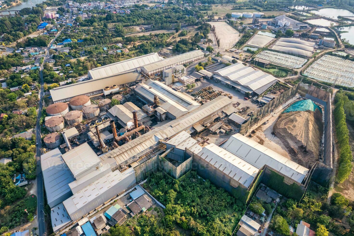 Sugar cane biomass processing plant with warehouse, tank and harvester truck in factory photo