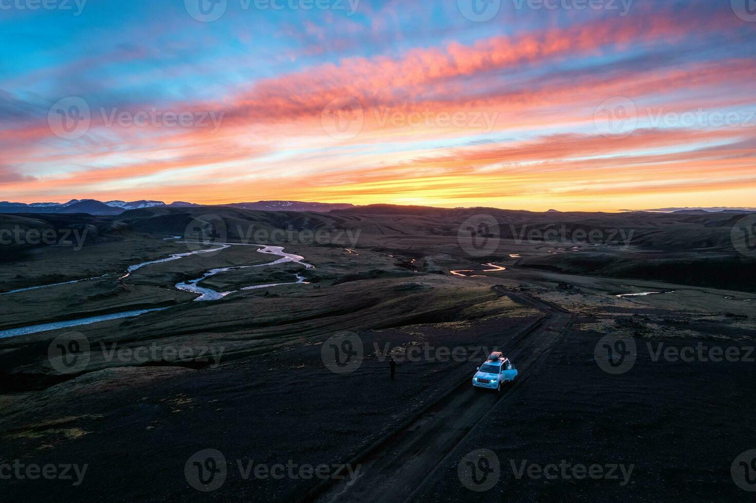 4wd car parked on dirt road among moss lava field in the sunset on Icelandic highlands in summer of Iceland photo