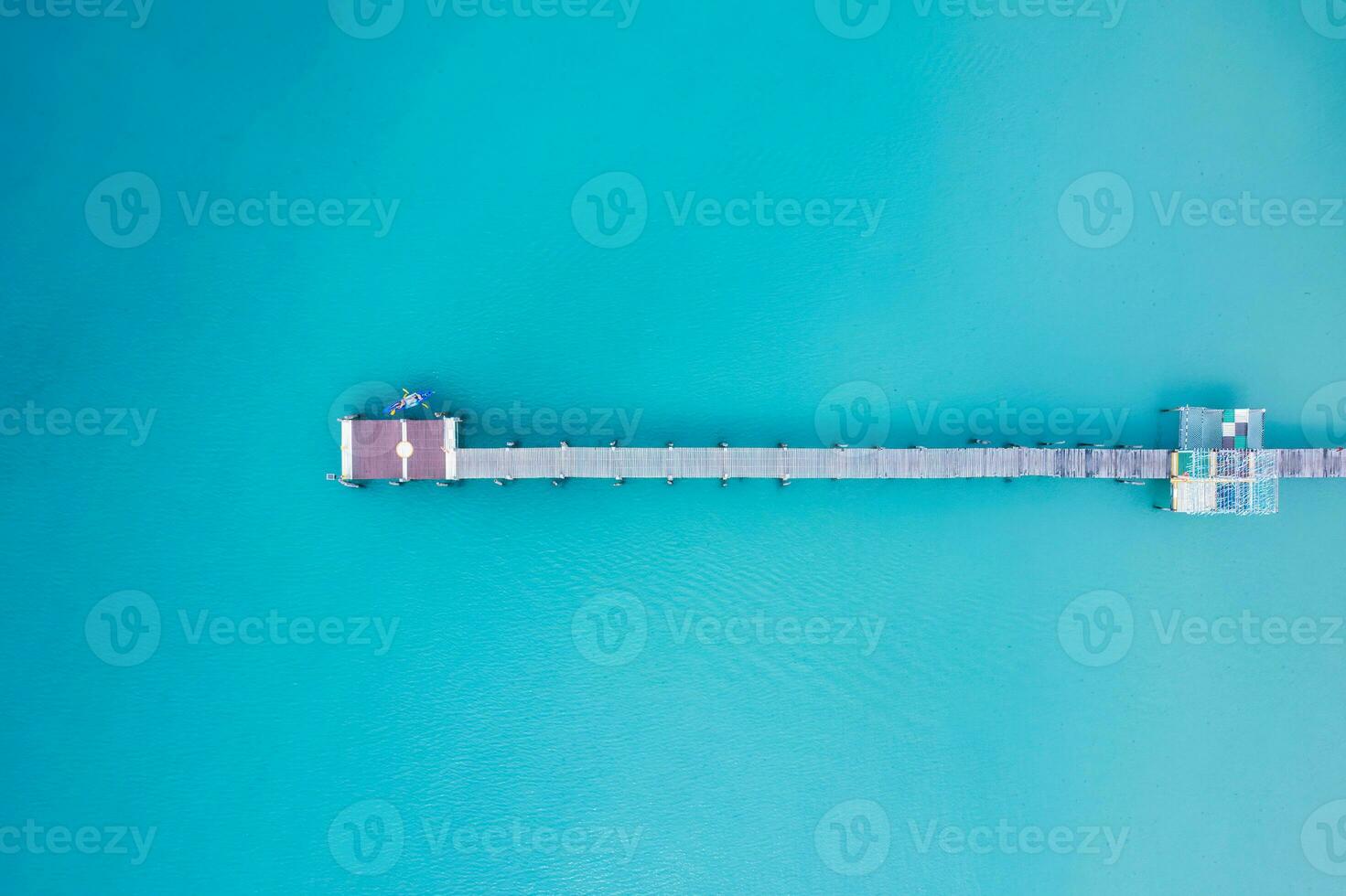 Top view of tourist canoeing by wooden pier in turquoise sea on summer at tropical island photo