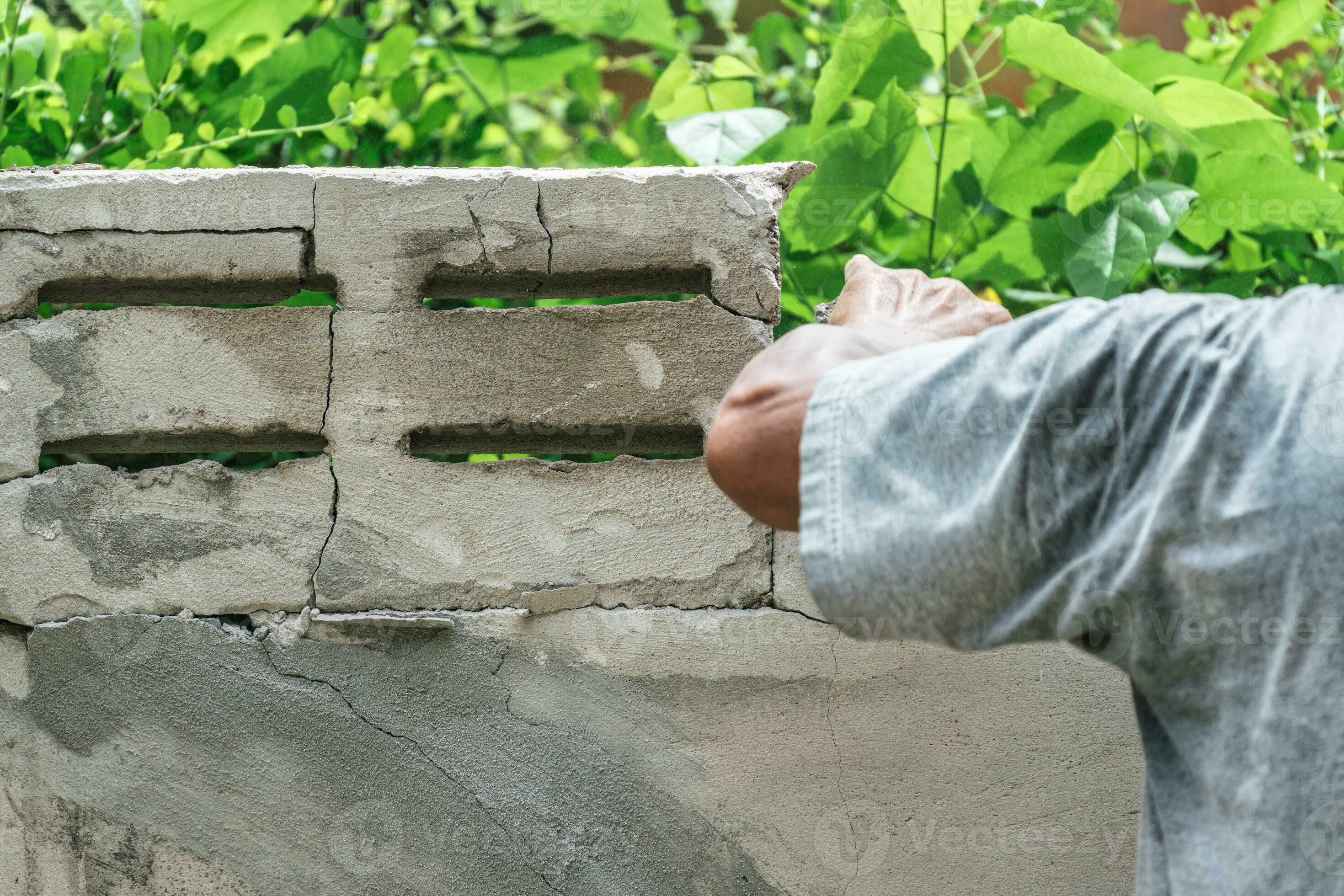 Hand of worker using hammer smashing and demolish on brick wall at