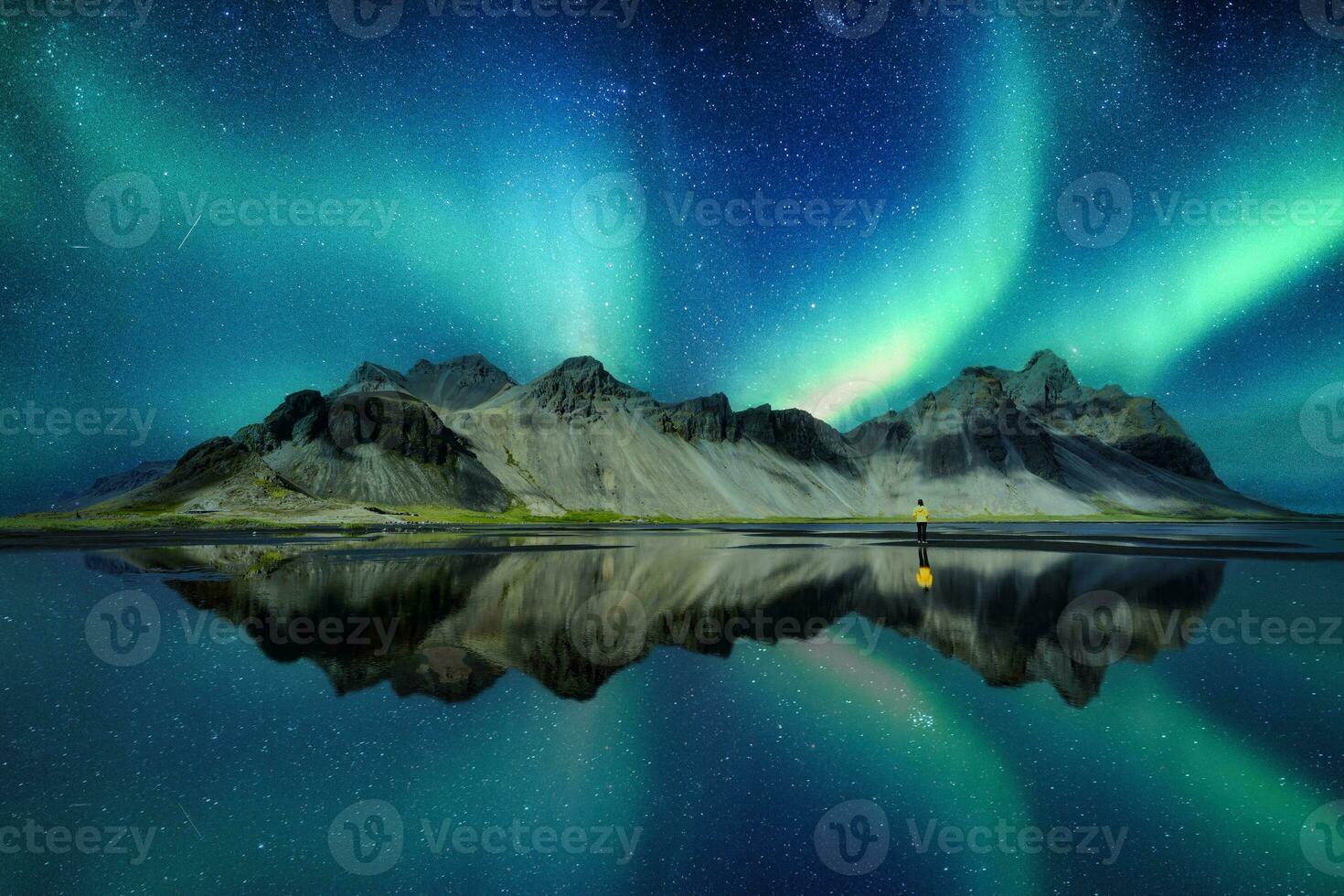 Landscape of Aurora borealis glowing over Vestrahorn mountain in viking village on Stokknes Peninsula at Iceland photo