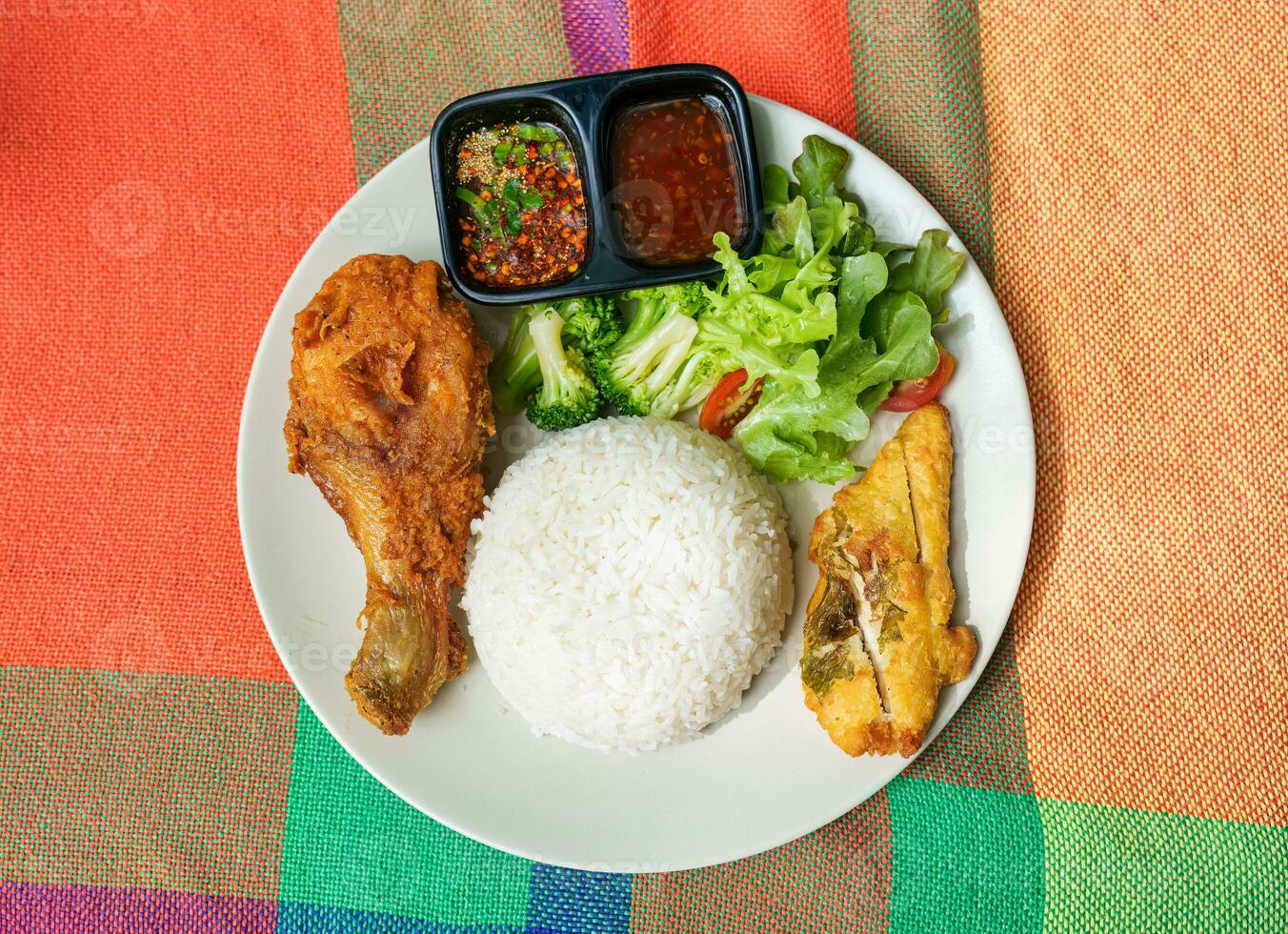 Fried chicken drumstick with crunchy chicken, rice, spicy sauce and vegetable on white plate photo