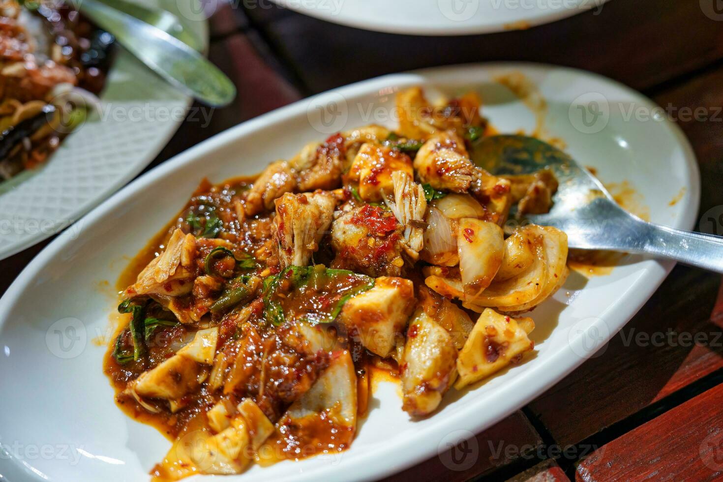 Stir fried chicken meat with chili paste sauce and herbs in white plate photo