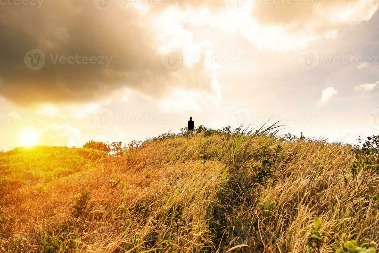 sillouette hombre estar en pico montaña prado dorado foto