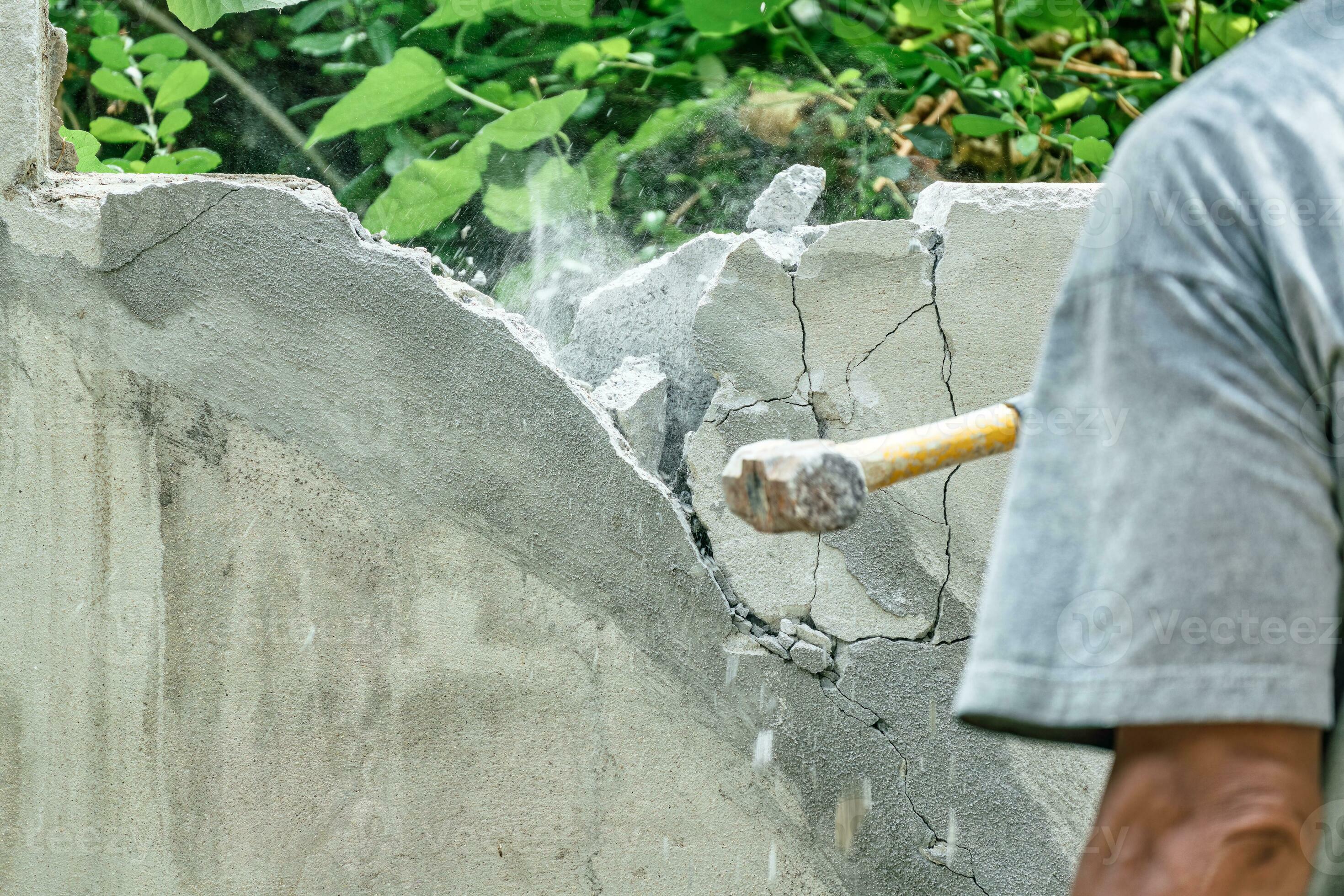 Hand of worker using hammer smashing and demolish on brick wall at
