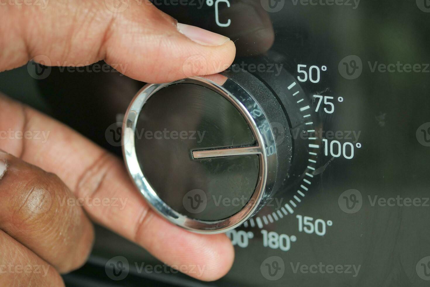 woman hand setting temperature control on oven. photo