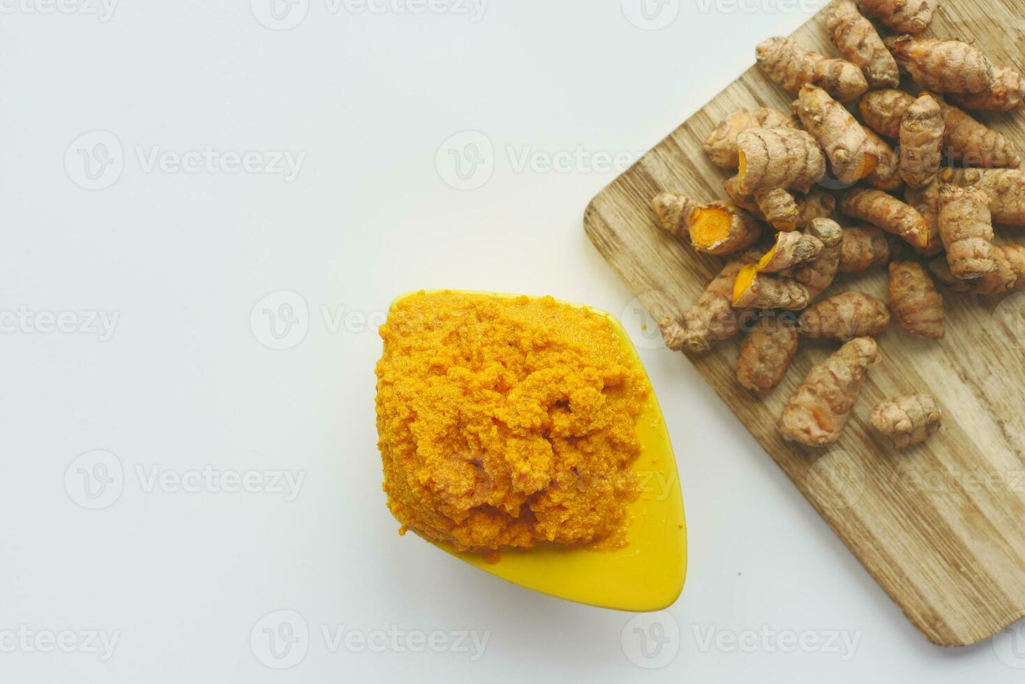 turmeric root and paste in a bowl on white background photo