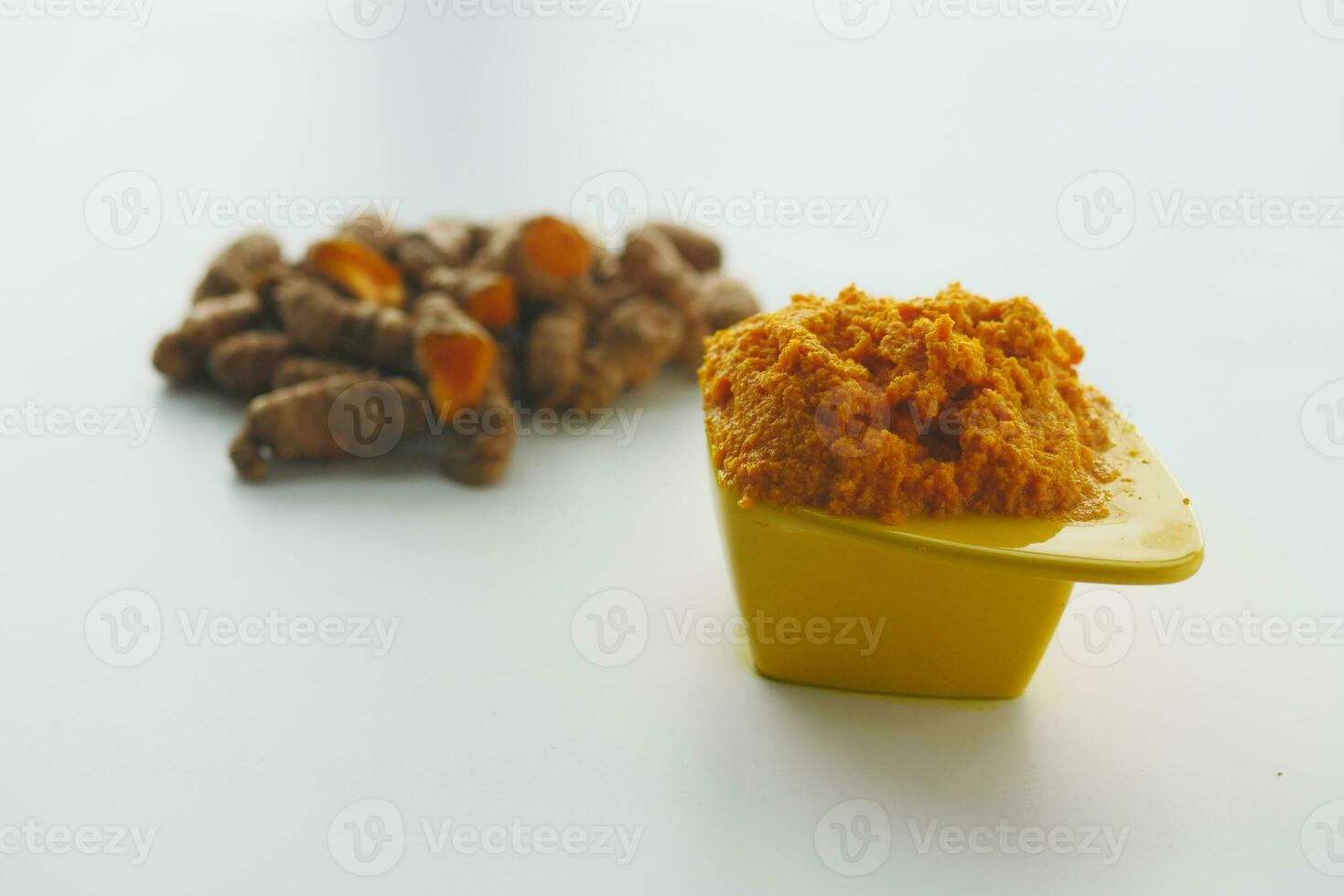 turmeric root and paste in a bowl on white background photo