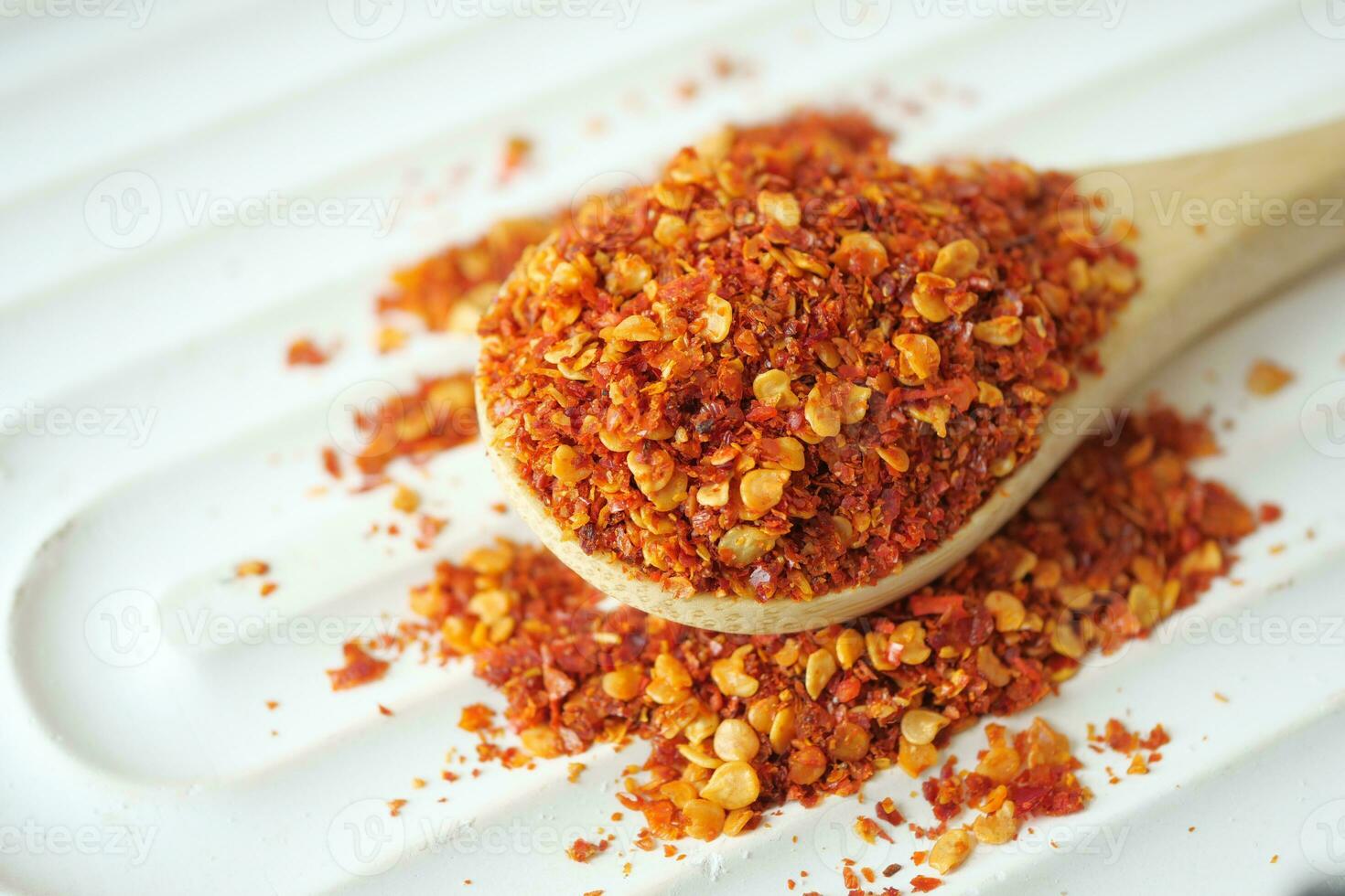 chili flakes on a wooden spoon on table photo