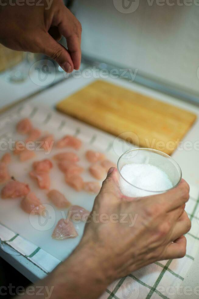Unrecognizable person salting diced chicken photo