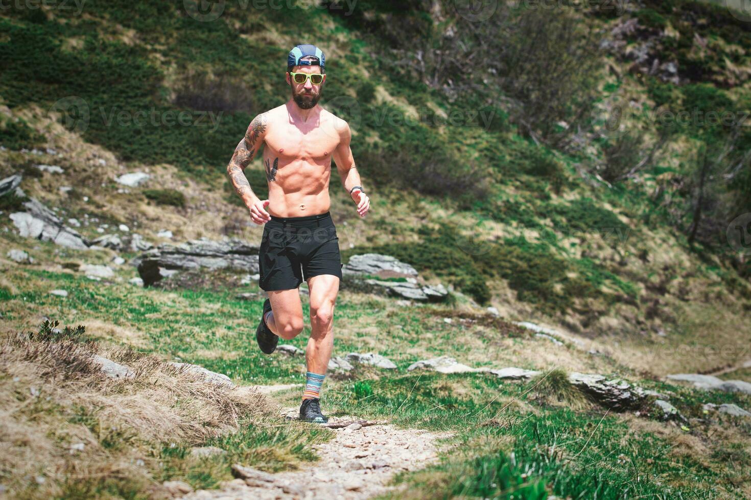 A sporty man with muscles runs on a mountain trail photo