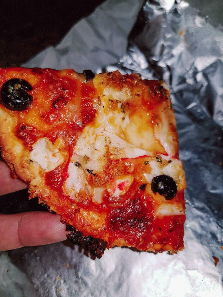 sabroso pedazo de Pizza en mano para Pizza amantes foto