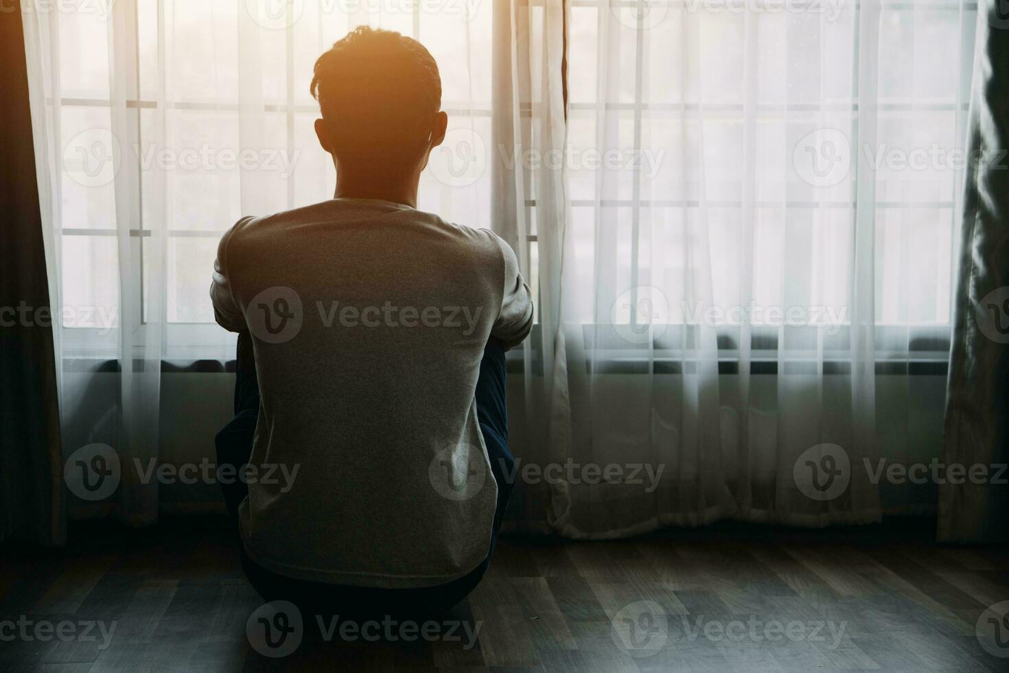 Alone man silhouette staring at the window closed with curtains in bedroom. Man stands at window alone photo
