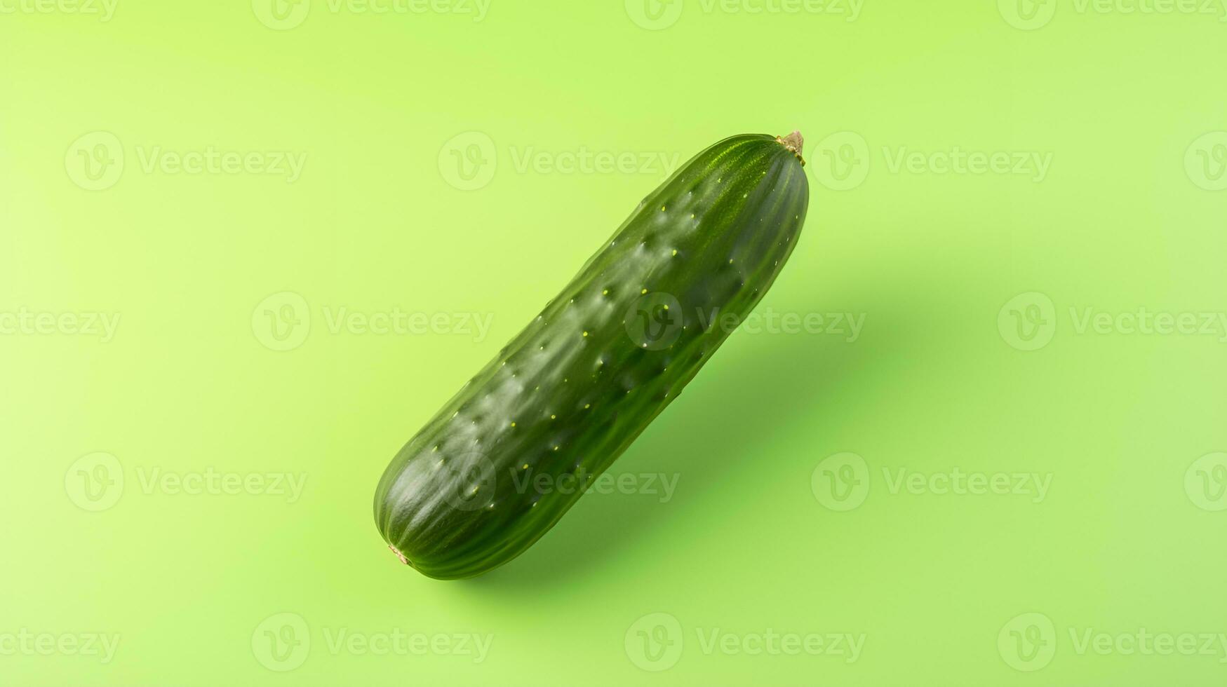 A single cucumber on a pastel green background. photo