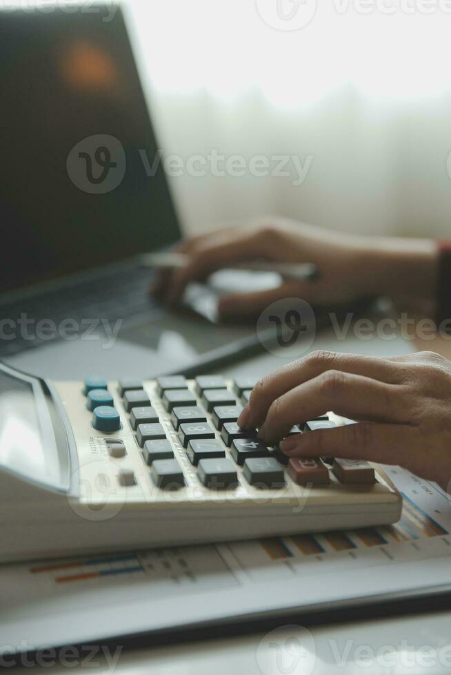 Close up businessman hand using calculator and working with laptop calculate about finance accounting at coffeeshop outdor.finance accounting concept photo