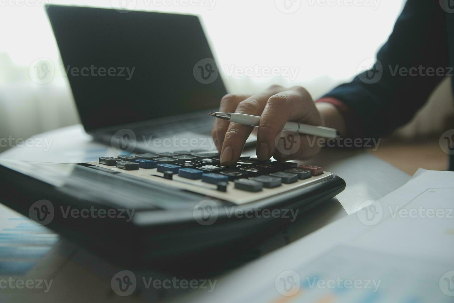 Close up businessman hand using calculator and working with laptop calculate about finance accounting at coffeeshop outdor.finance accounting concept photo