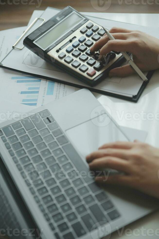 Close up woman hand using calculator and writing make note with calculate about cost at home office. photo