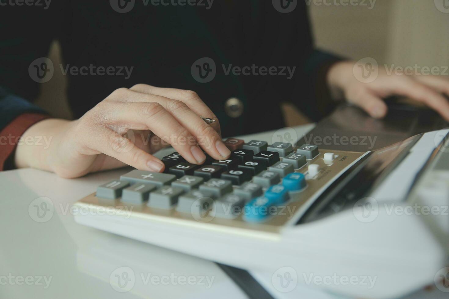 Woman entrepreneur using a calculator with a pen in her hand, calculating financial expense at home office photo
