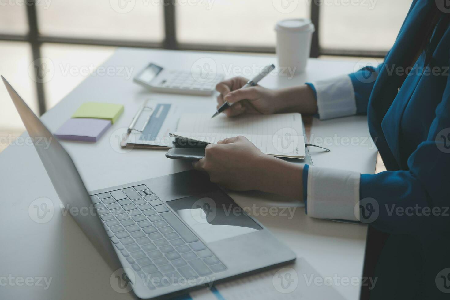 Asian Business woman using calculator and laptop for doing math finance on an office desk, tax, report, accounting, statistics, and analytical research concept photo