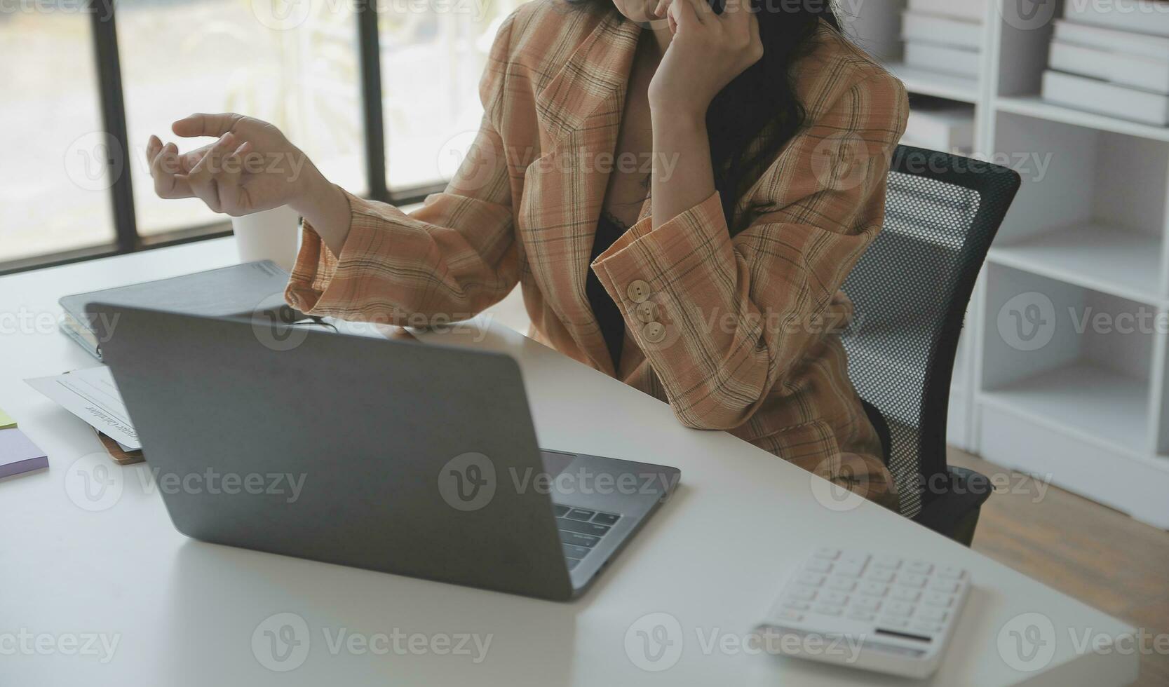 Asian Business woman using calculator and laptop for doing math finance on an office desk, tax, report, accounting, statistics, and analytical research concept photo