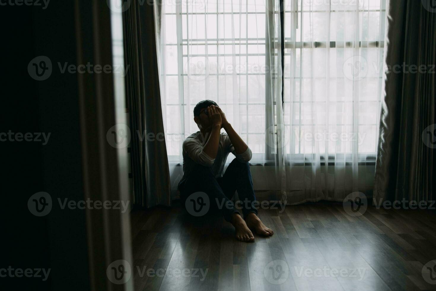 Alone man silhouette staring at the window closed with curtains in bedroom. Man stands at window alone photo