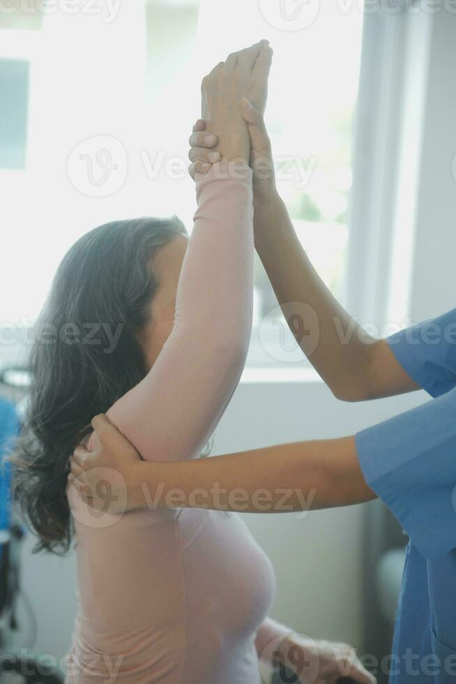 Doctor or physical therapist examines back pain and spinal area to give advice within the rehabilitation center. photo