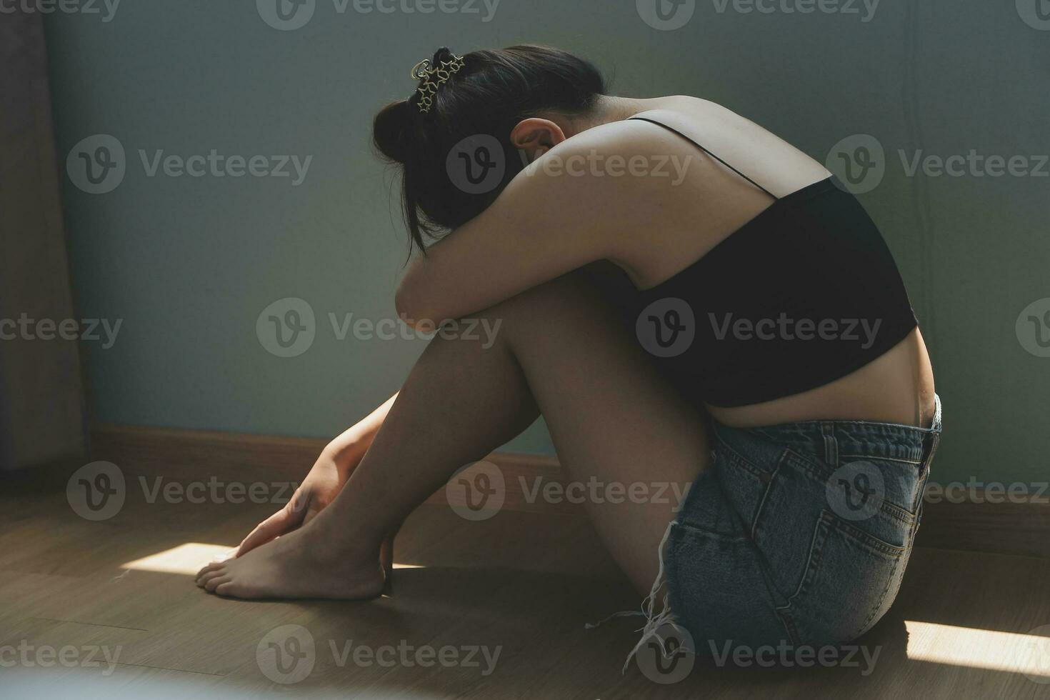 pensativo niña sentado en umbral abrazando rodillas mirando a ventana, triste Deprimido adolescente gasto hora solo a hogar, joven trastornado pensativo mujer sensación solitario o frustrado pensando acerca de problemas foto