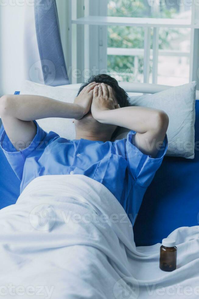 young injured man in hospital room sitting alone in pain looking negative and worried for his bad health condition sitting on chair suffering depression on a sad lonely medical background photo