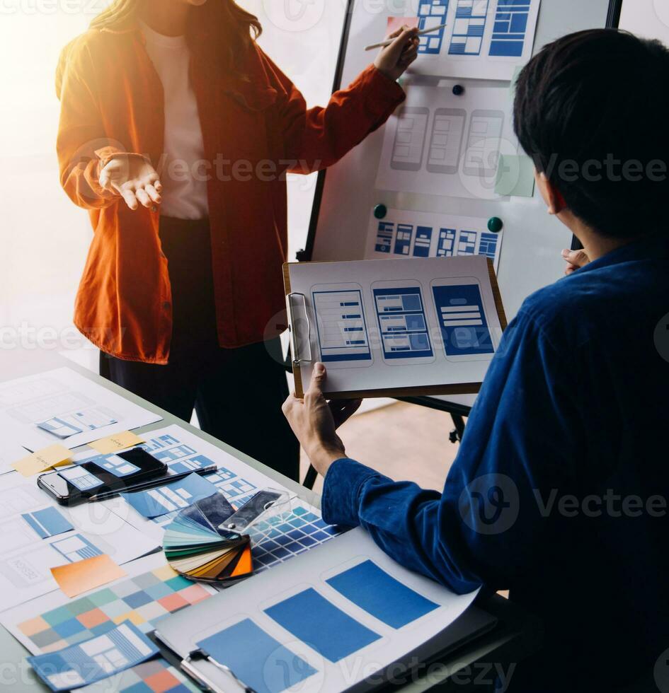 Close up ux developer and ui designer brainstorming about mobile app interface wireframe design on table with customer breif and color code at modern office.Creative digital development agency photo